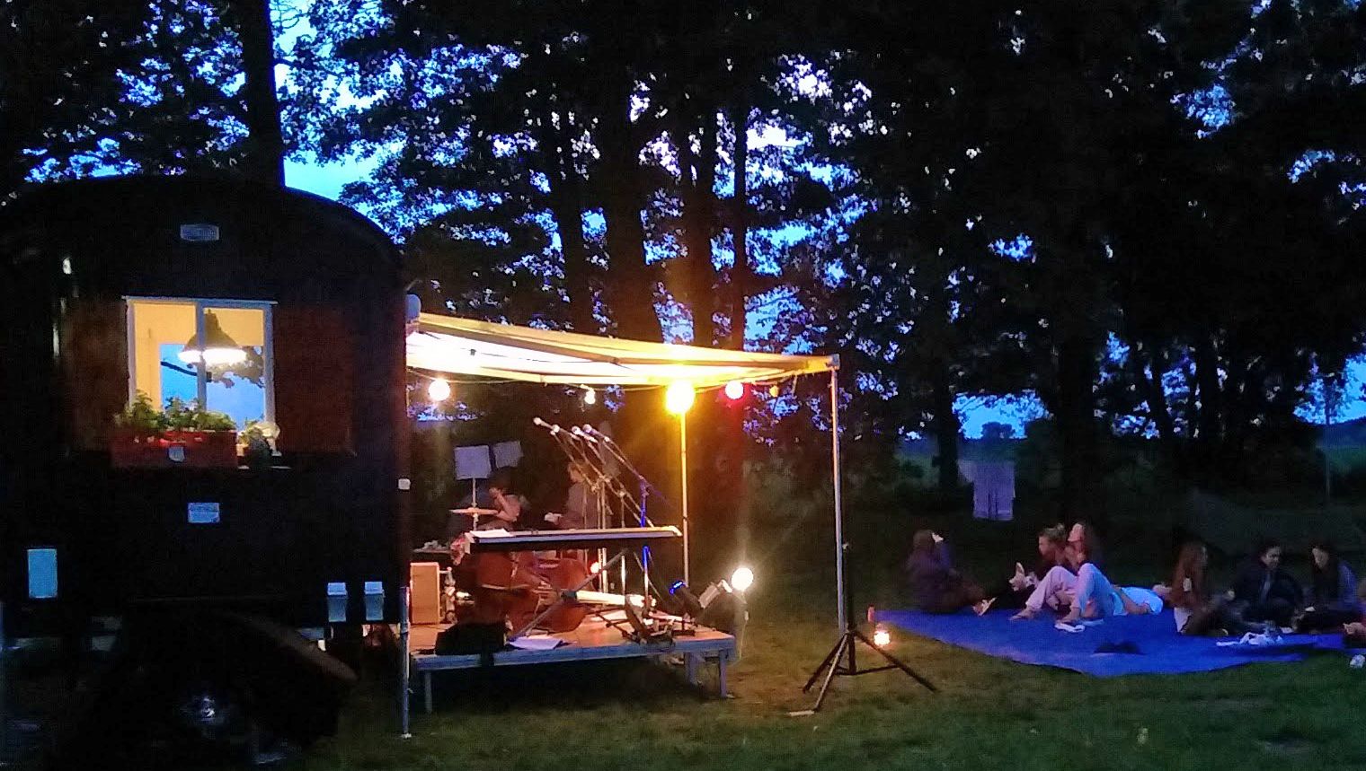 Jugendliche sitzen auf Bänken in einem Zelt, vor ihnen regnet es Konfetti