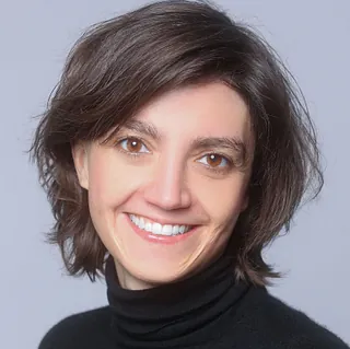 Profilfoto von Anna Jakob. Sie hat kinnlanges, dunkles Haar und trägt einen schwarzen Rollkragenpullover